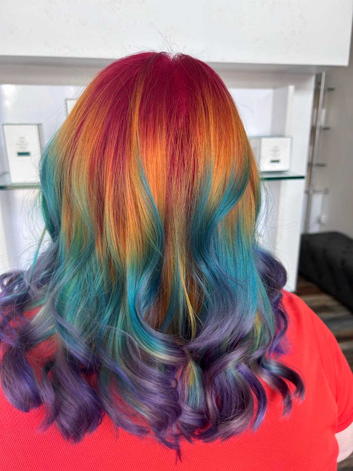 Multicolored hair with vibrant red, orange, blue, and purple hues, styled in loose curls.