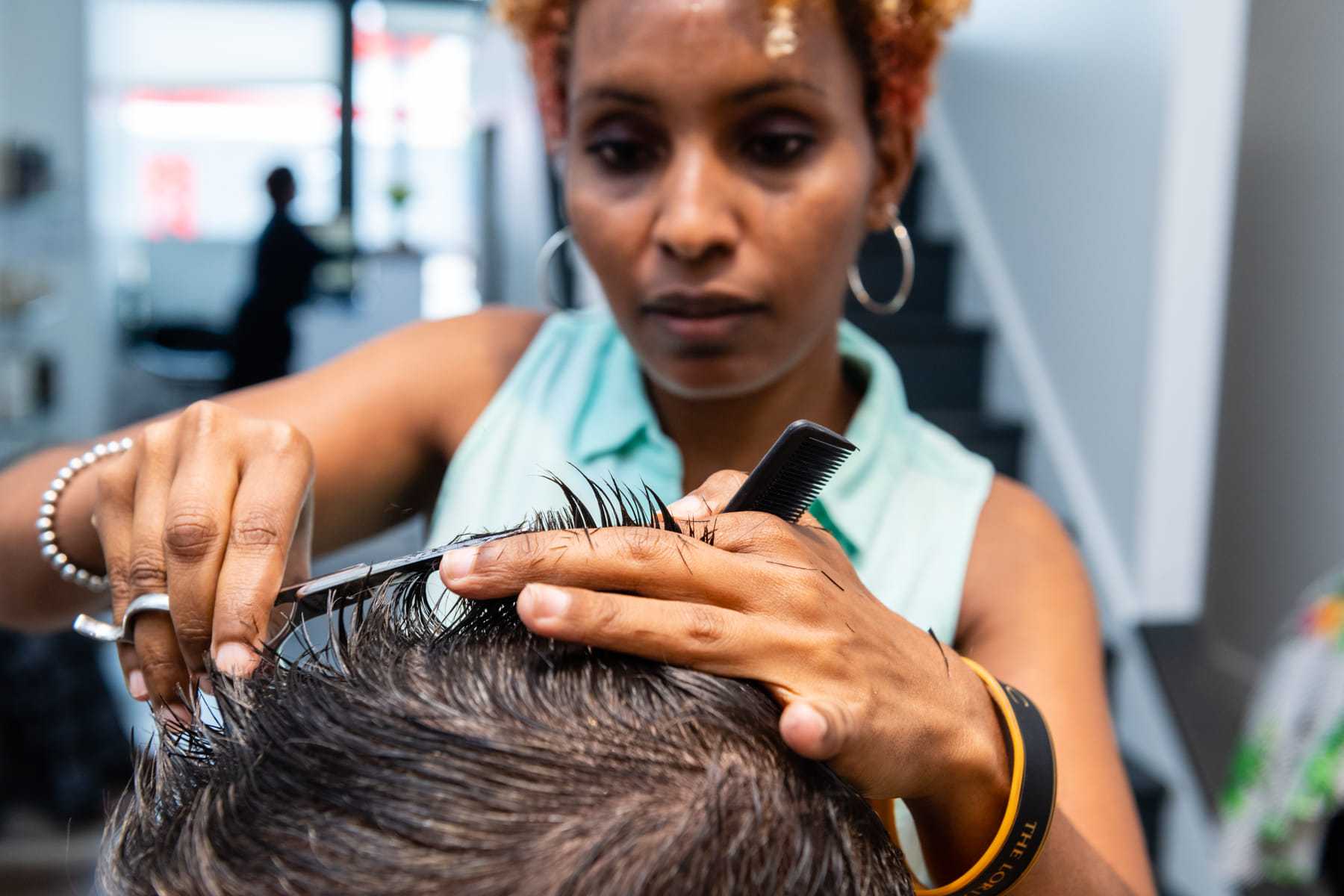 Hairstylist cutting a client's hair in a modern salon setting.