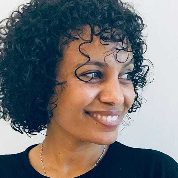 Portrait of Seghen Tekle, a professional stylist at Eden DC Salon, showcasing their expertise and style.